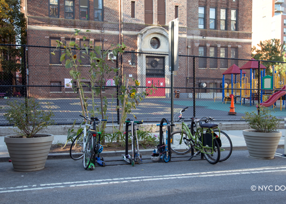 Image of a bike corral with bikes parked and planters on either side all in the roadway.