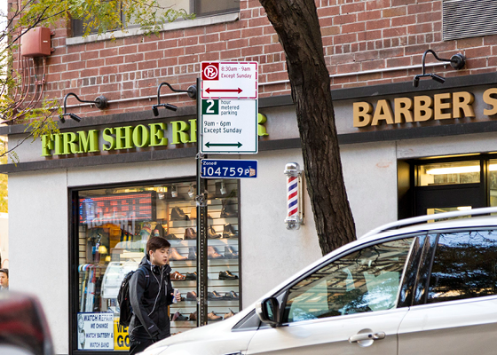 Photo showing a car with a 2 hour metered parking sign behind.