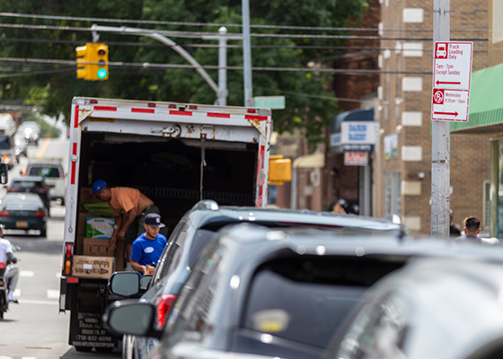 Photo of a truck unloading with a truck loading only sign mounted to a light pole.