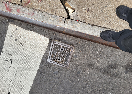 Photo showing a water shut-off valve in the roadway next to the curb.