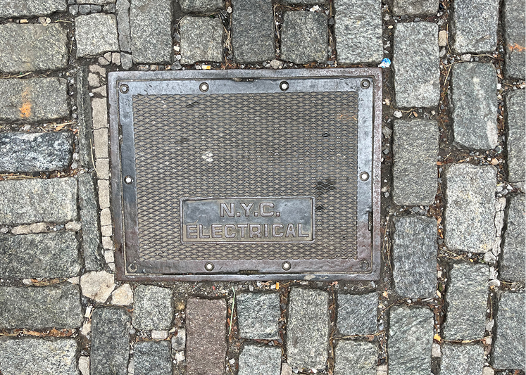 Photo of an NYC Electrical pull box in a cobblestone street.