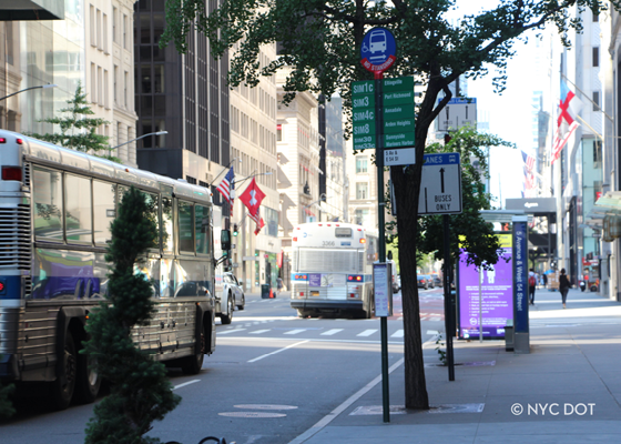 Image of a bus shelter in the background and bus stop pole in the foreground