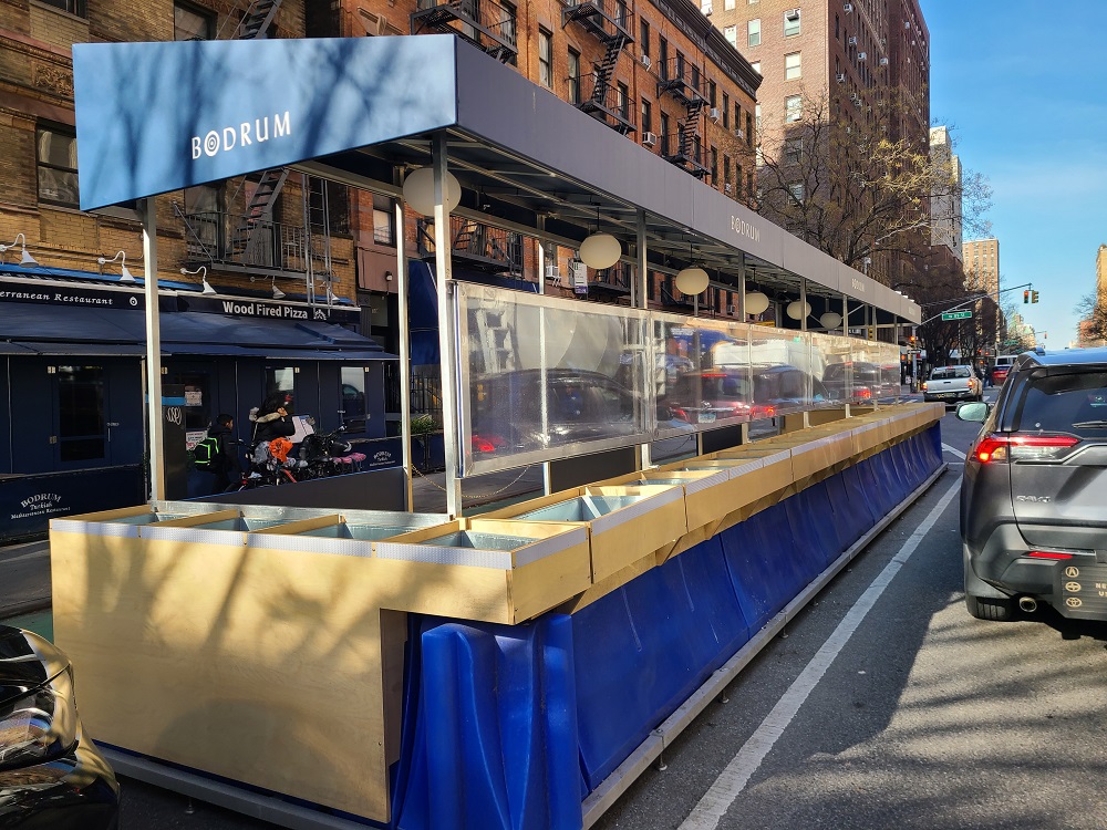 A view from the roadway of the floating parking lane prototype with vertical panels between the roadway and cafe dining area