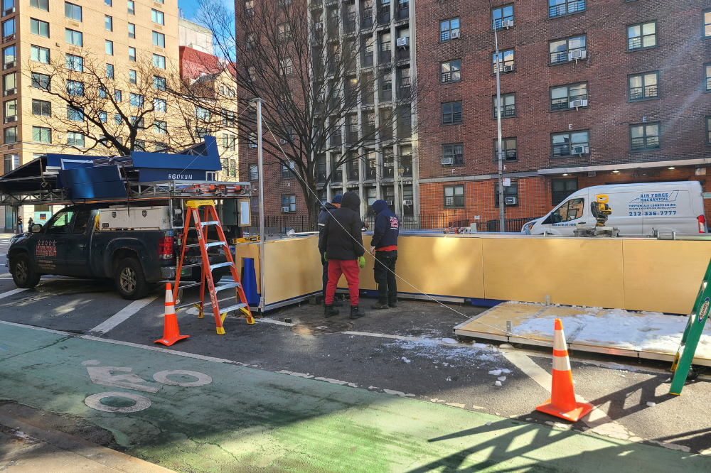 A team assembles a floating parking lane barrier on a street with snow