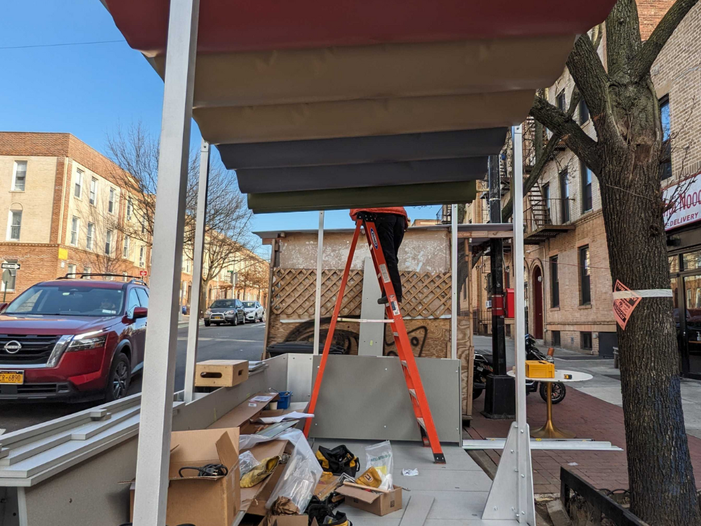 A person opens the overhead covering on a steep street roadway cafe